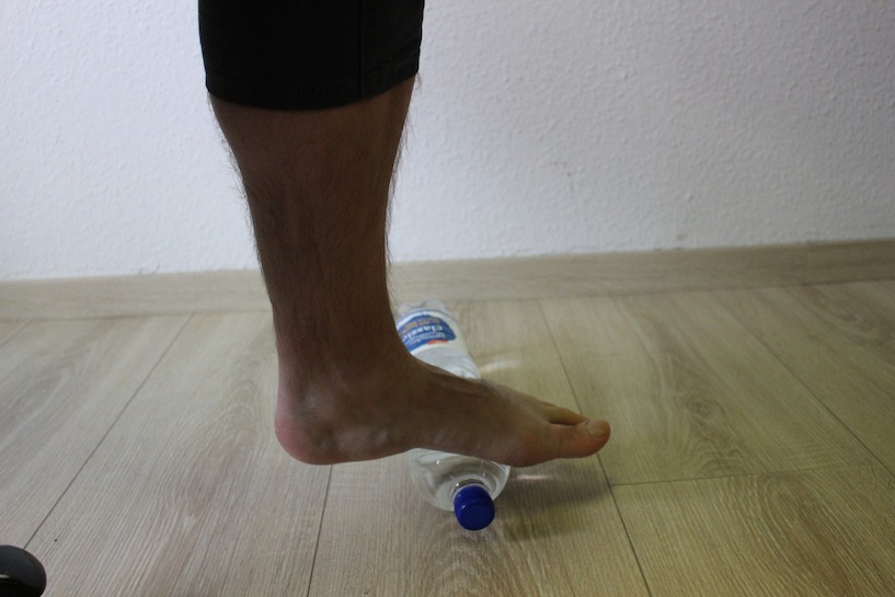 Statt eines Tennisballs kann auch eine kleine Wasserflasche für die Übung verwendet werden. Fuß, rollen, Fußgymnastik